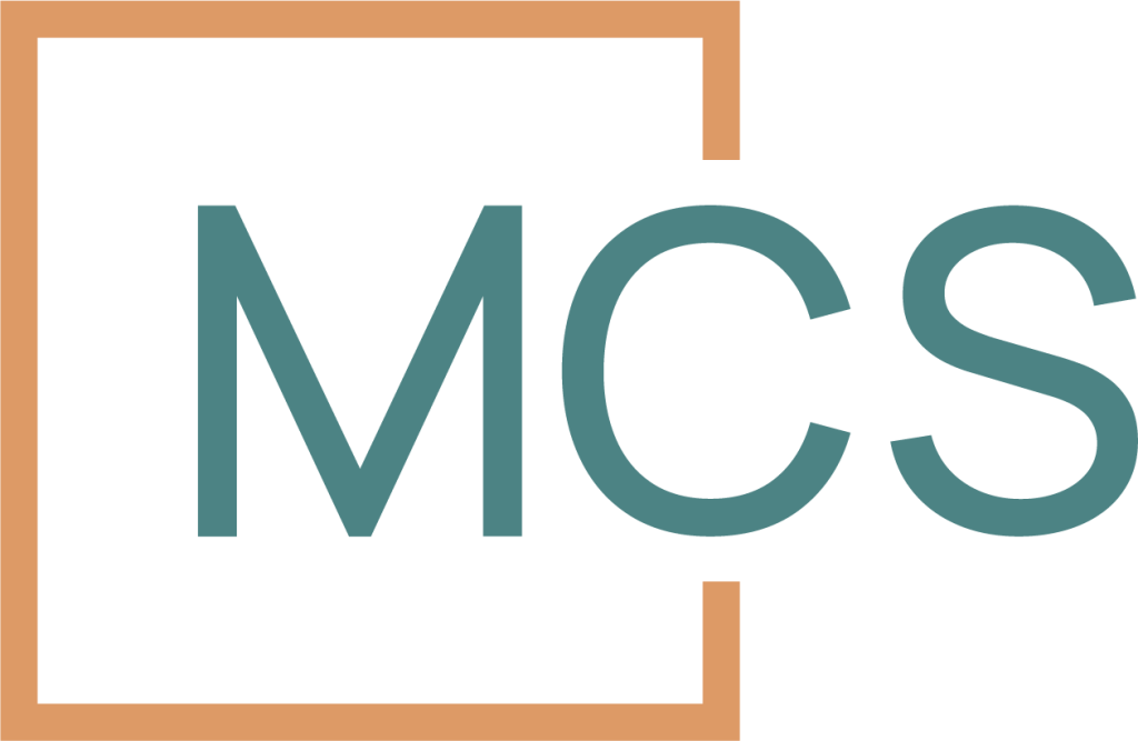 Logo with the letters "MCS" in teal, partially enclosed by an open-ended orange square bracket on the left side. The background is white.